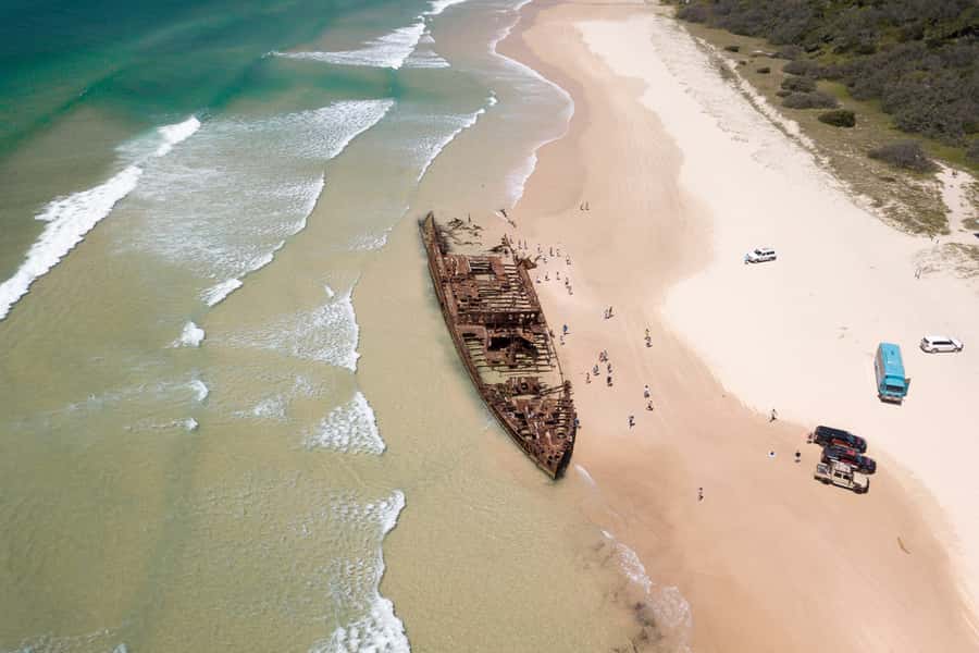 From Rainbow Beach: K'gari, Fraser Island Two-Day Coach Tour - 75 Mile Beach, a road with waves on one side